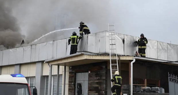 Firefighters work to extinguish a blaze on the roof of a damaged building hit by shelling in Belgorod, Russia, March 17, 2024 [Governor of Belgorod Region/Vyacheslav Gladkov via Telegram/Handout via Reuters]